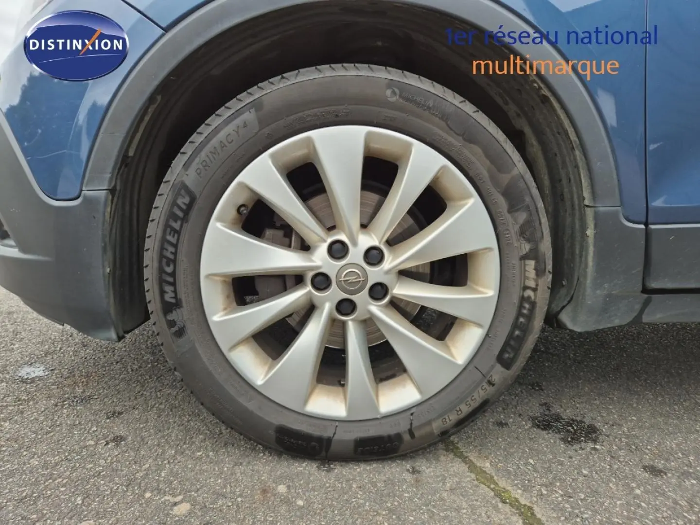 Gros plan sur la roue avant gauche d’un Opel Mokka bleu outremer avec jante alu et pneu Michelin.