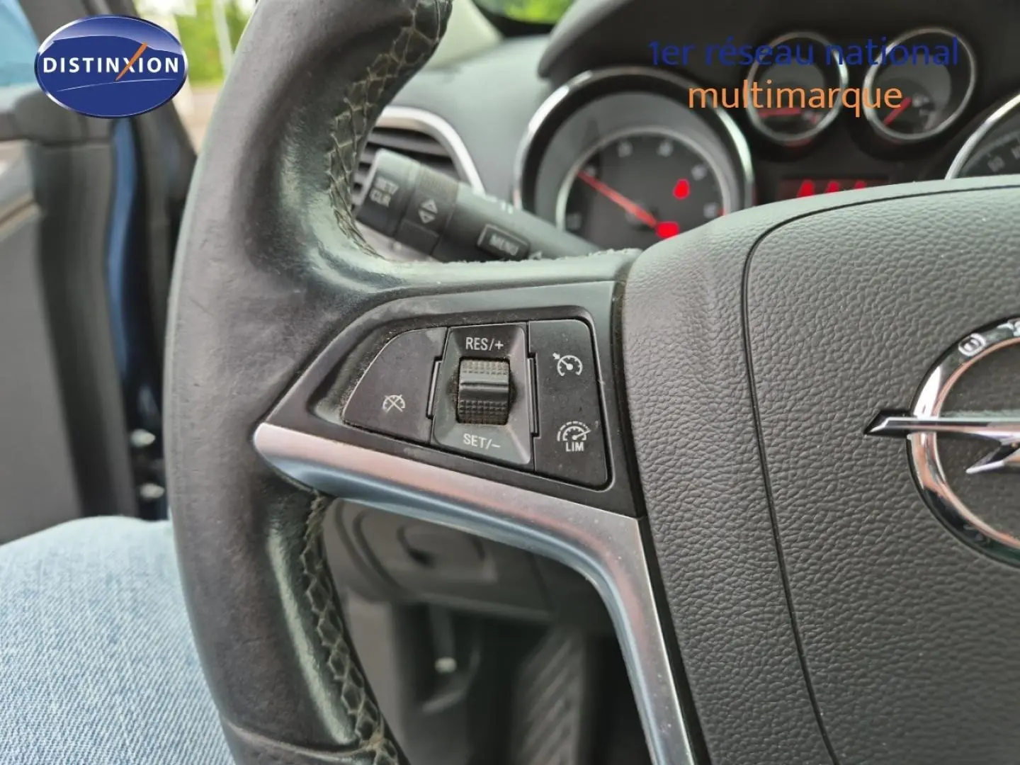 Gros plan sur le volant cuir de l'Opel Mokka 2015, montrant les commandes de régulateur de vitesse côté gauche.