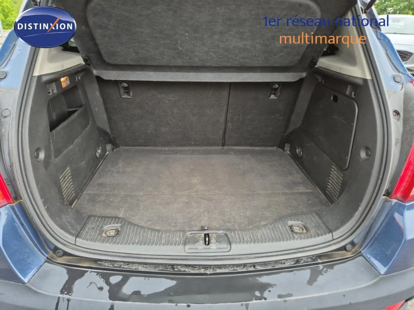 Coffre ouvert d’un Opel Mokka bleu outremer, vue arrière montrant l’espace de chargement vide et les parois intérieures noires.