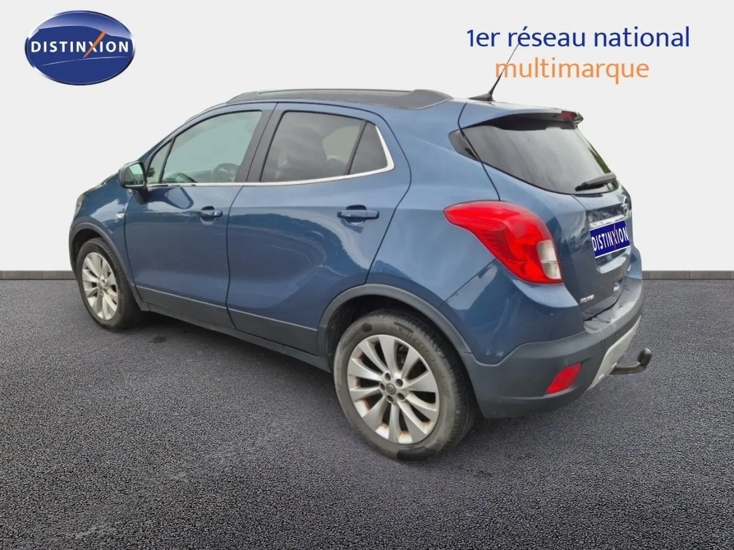 Opel Mokka bleu outremer vu de trois quarts arrière droit, avec barres de toit et jantes alu visibles.