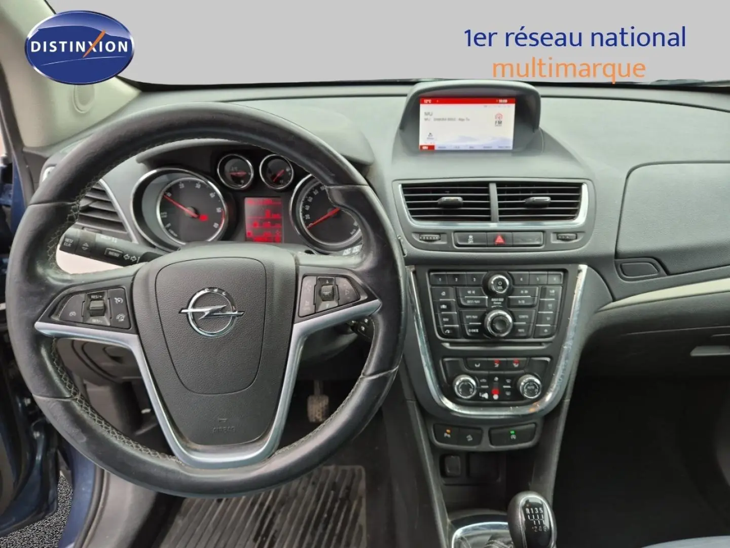 Vue intérieure centrée sur le volant cuir Opel Mokka bleu outremer avec tableau de bord et console centrale détaillée.