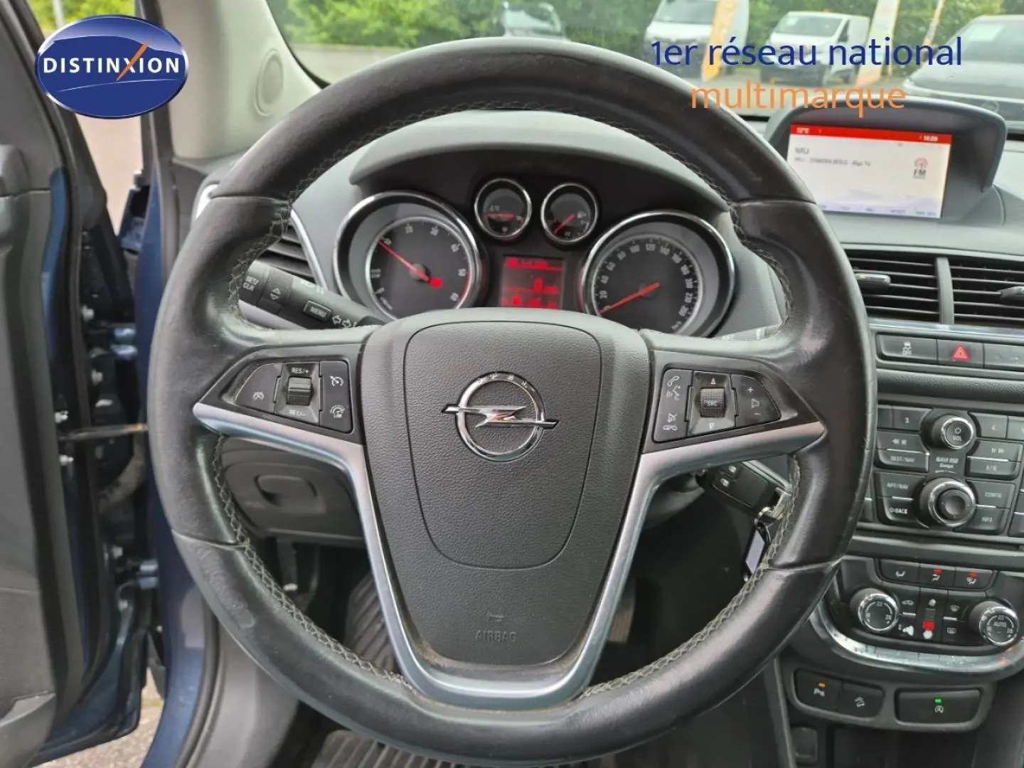 Vue intérieure centrée sur le volant cuir Opel Mokka bleu outremer, avec tableau de bord et console centrale visibles.