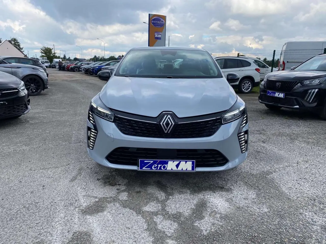 Vue frontale d'une Renault Clio 2025 gris rafale avec éclairage LED et plaque d'immatriculation Zero KM visible.