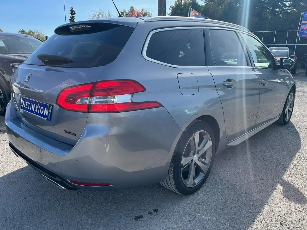 Peugeot 308 SW gris clair vue 3/4 arrière droit, avec vitres surteintées et jantes alliage 17 pouces diamantées.