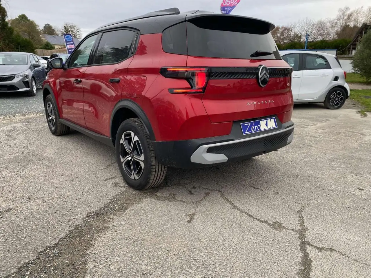 Vue 3/4 arrière droite du Citroën C3 Aircross rouge Elixir avec toit noir et feux arrière LED 3D sur parking.