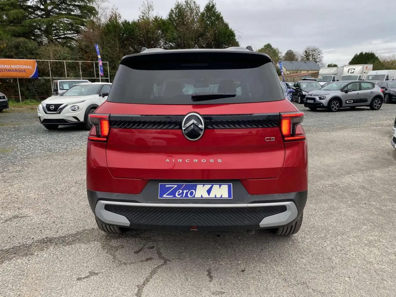 Vue arrière d'un Citroën C3 Aircross rouge Elixir avec toit noir et feux arrière LED 3D allumés.