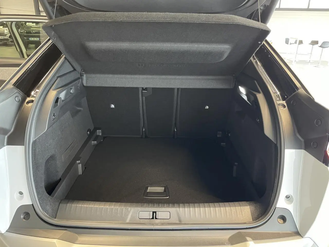 Coffre ouvert vu de l'arrière d'un Peugeot 3008 blanc Okenite avec intérieur noir et habillage soigné.