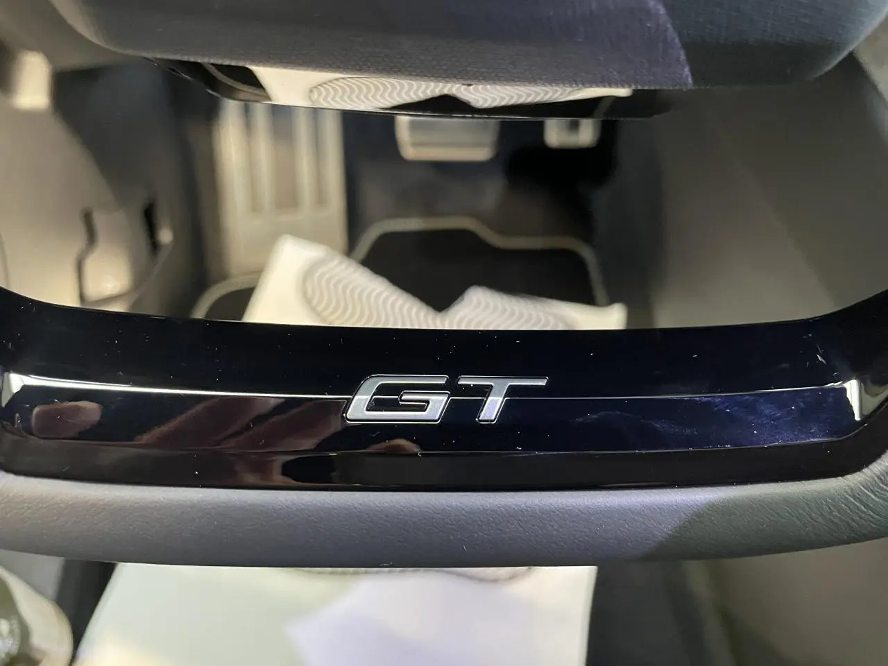 Gros plan sur le badge GT noir laqué sur la console centrale du Peugeot 3008 blanc Okenite.