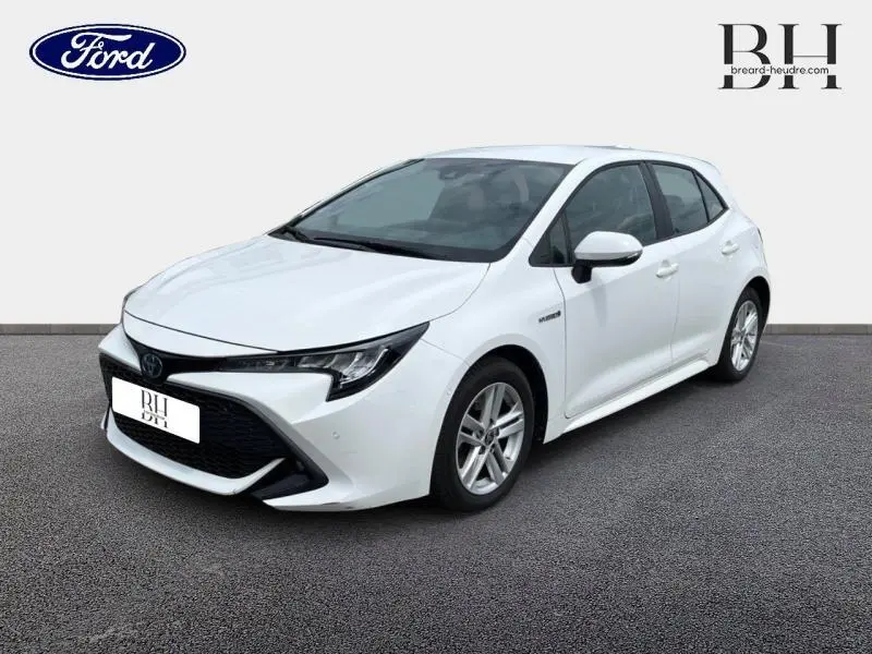 Toyota Corolla hybride blanc pur vue 3/4 avant droit avec calandre noire et jantes alu.