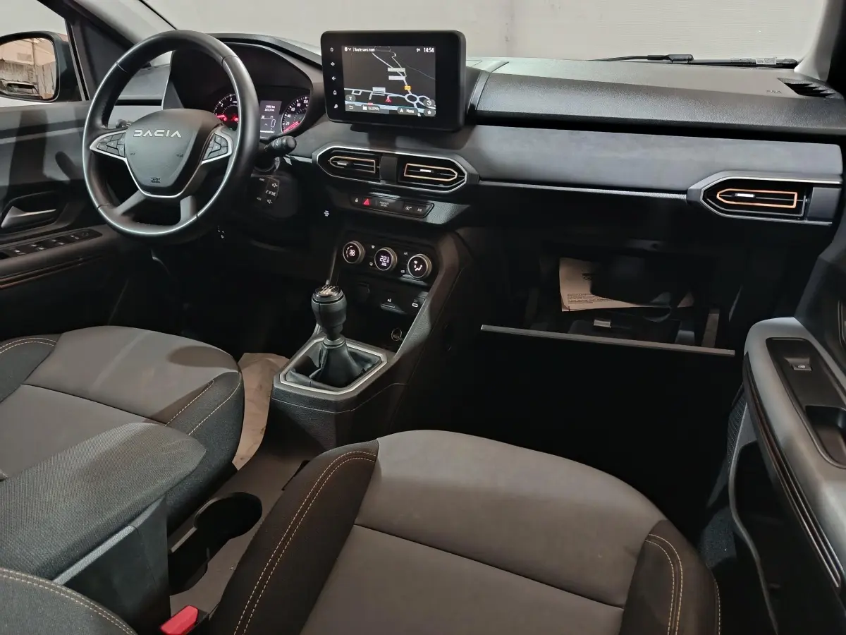 Vue intérieure avant droite du tableau de bord et volant cuir de la Dacia Sandero Extreme+ 2024 avec écran tactile et boîte manuelle.