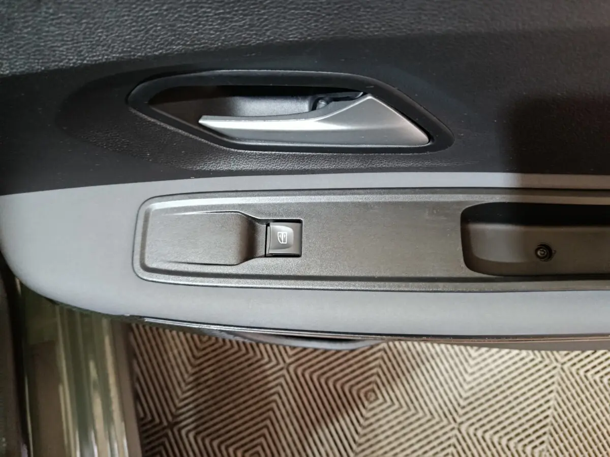 Gros plan sur la poignée intérieure et le bouton de lève-vitre côté conducteur de la Dacia Sandero Extreme+ TCe 110 verte 2024.