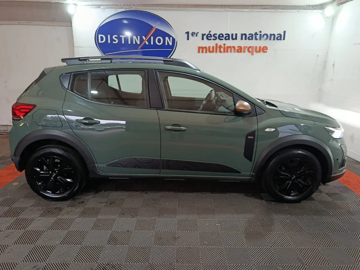 Vue de profil côté gauche d'une Dacia Sandero Extreme+ TCe 110 2024 verte avec jantes noires et rails de toit assortis.