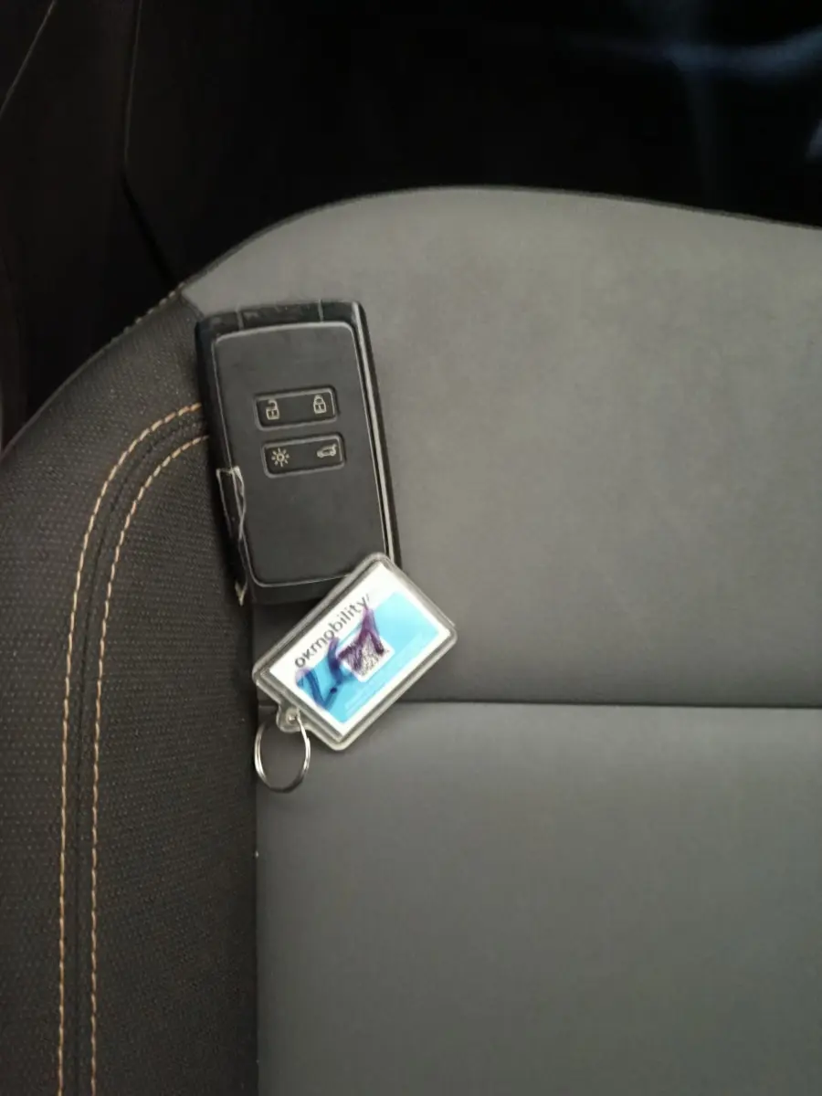 Clé de voiture noire posée sur un siège gris foncé avec surpiqûres beiges à l'intérieur d'une Dacia Sandero 2024.