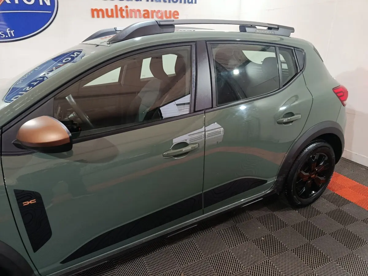Vue latérale gauche d'une Dacia Sandero Extreme+ 2024 vert avec rétroviseur cuivré et jantes noires distinctives.