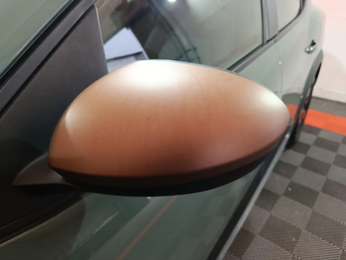 Rétroviseur droit vert métallisé de la Dacia Sandero Extreme+ 2024, vue rapprochée en intérieur sur sol damier.