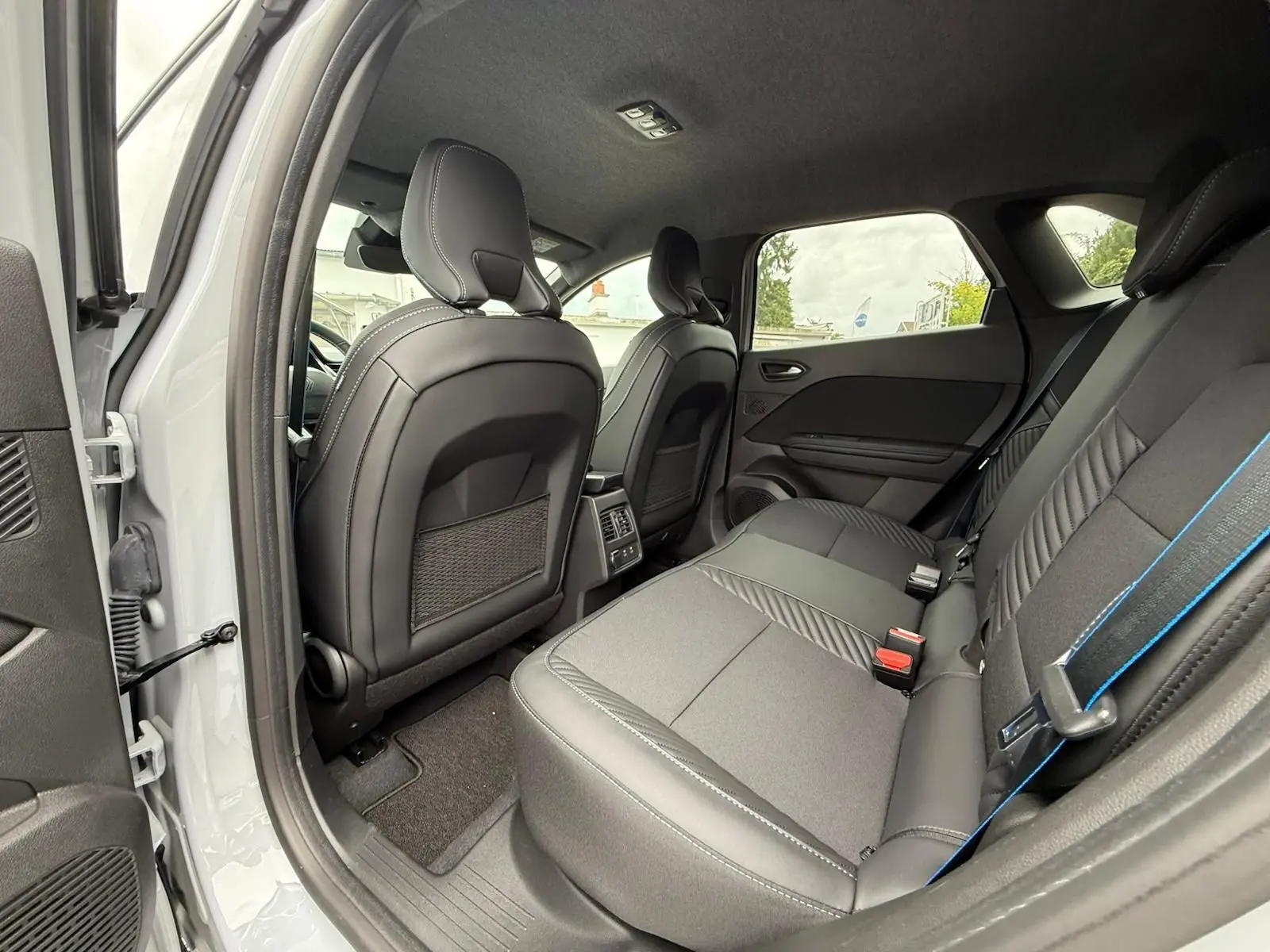 Vue intérieure arrière côté gauche du Renault Symbioz 2026 gris Rafale, montrant les sièges arrière et l'espace passager.