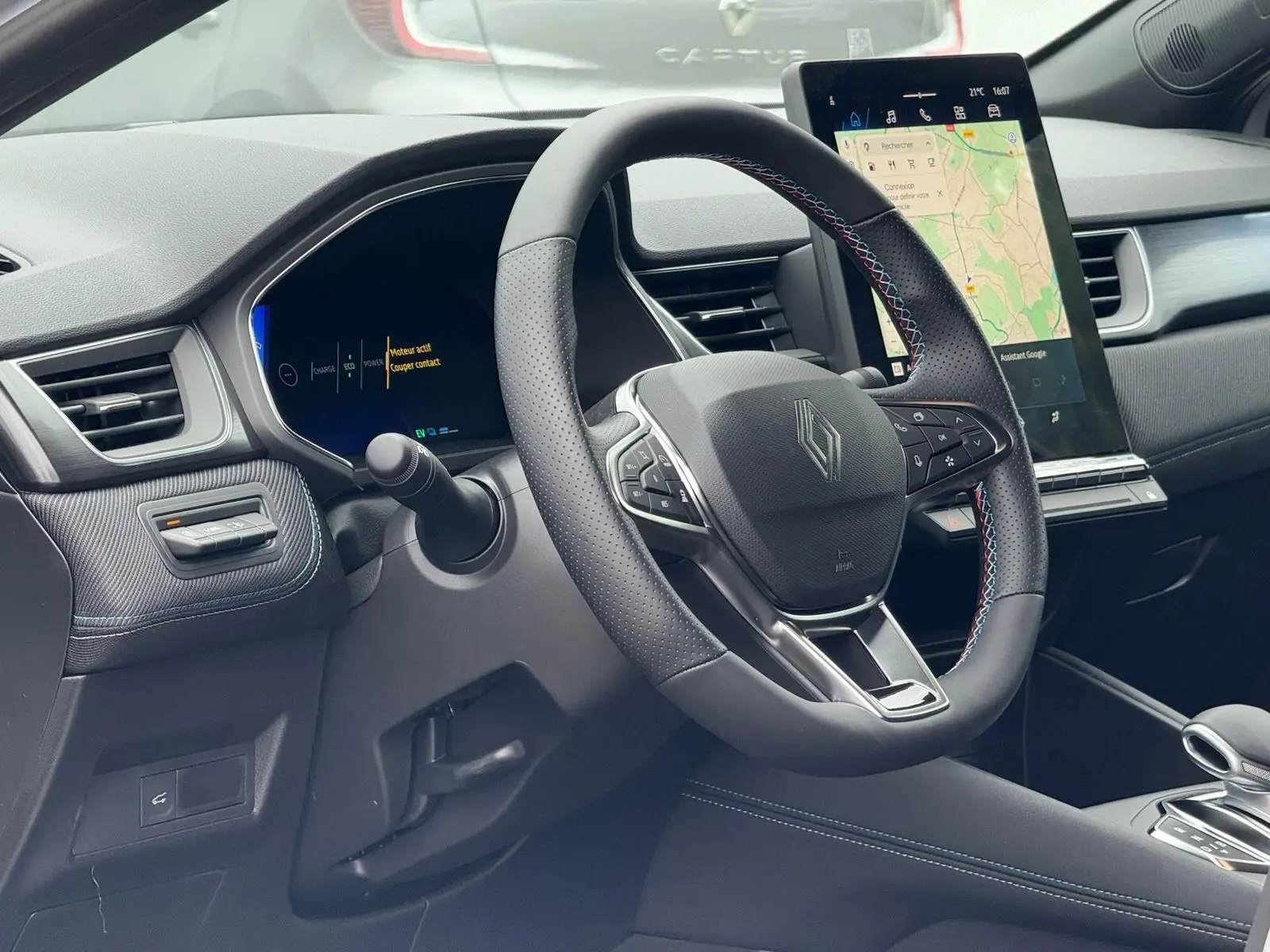 Vue intérieure côté conducteur du Renault Symbioz gris Rafale, volant multifonction et écran tactile vertical avec navigation.