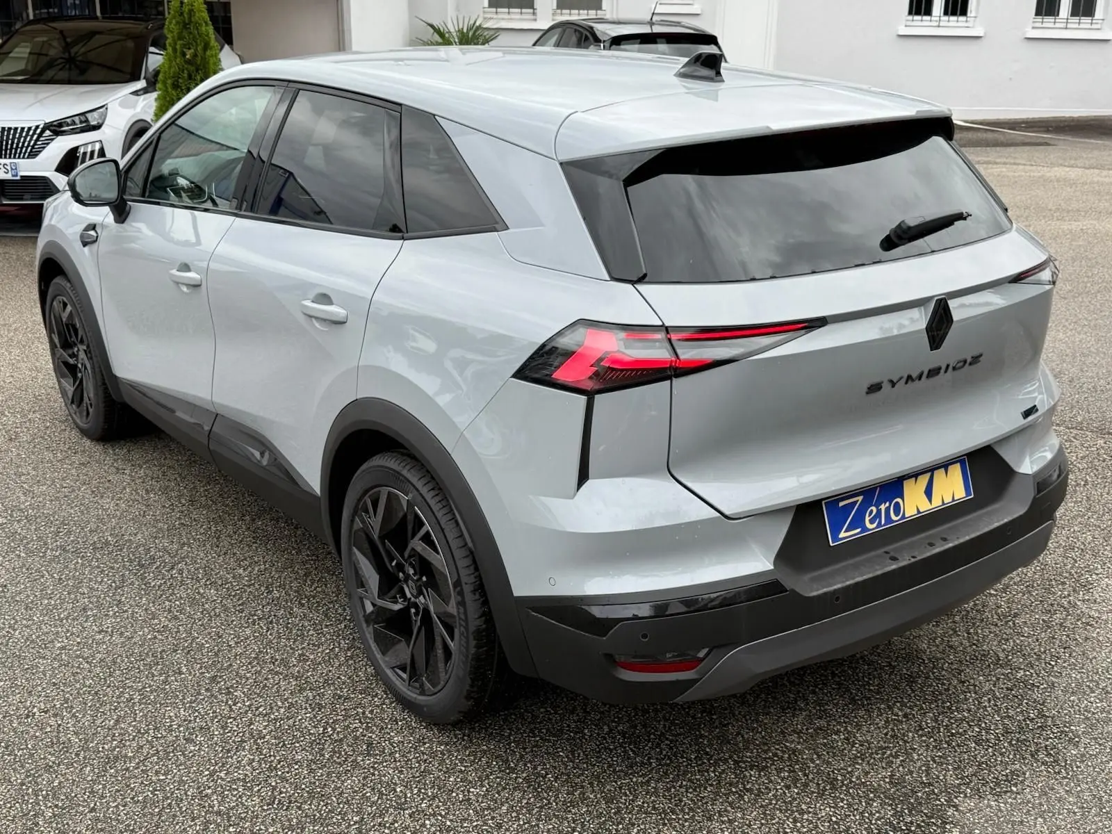 Vue 3/4 arrière droite du Renault Symbioz gris Rafale avec feux arrière LED et jantes noires distinctives.