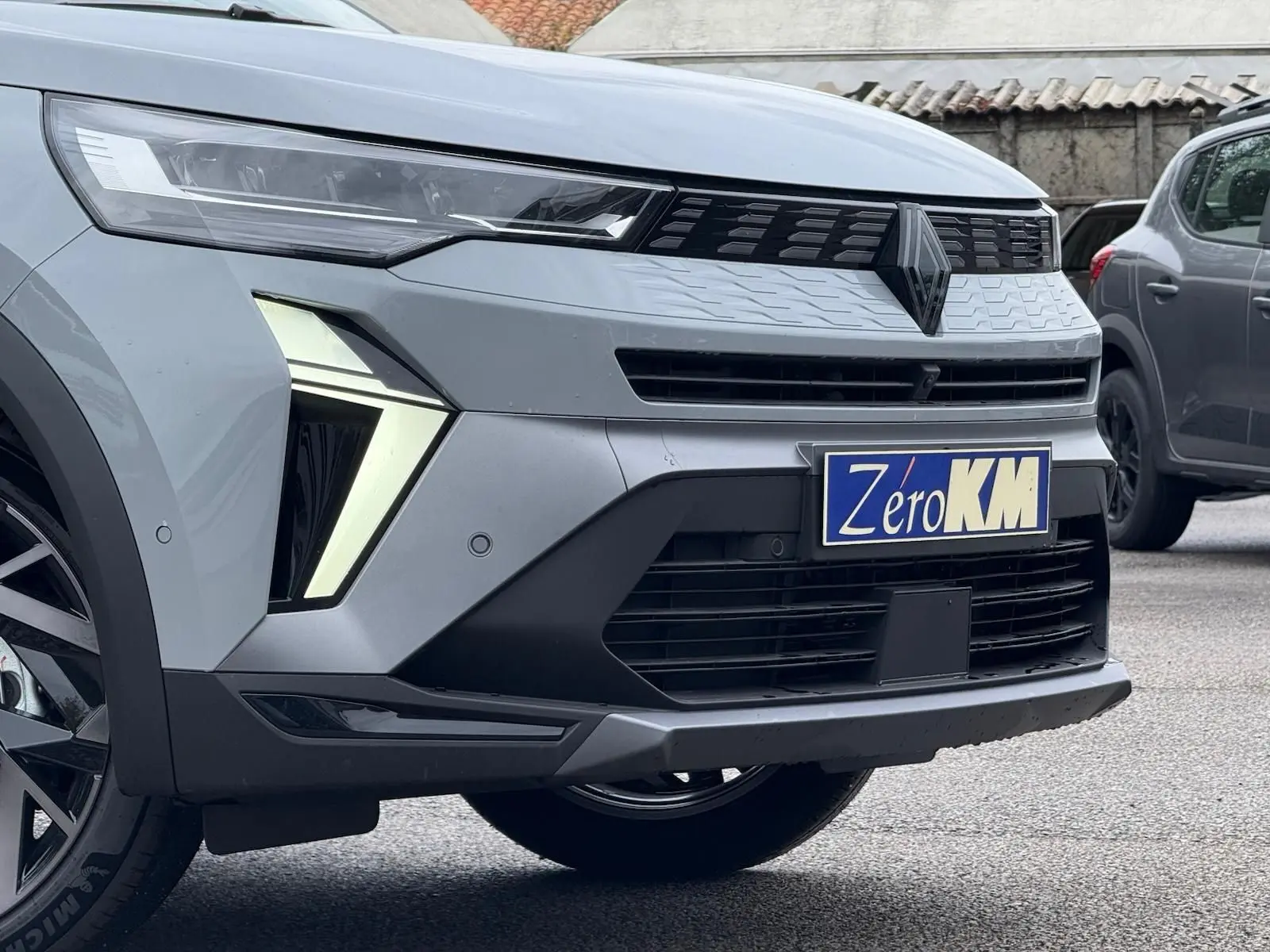 Vue avant droite du Renault Symbioz gris Rafale, mettant en valeur ses phares LED en forme de flèche et sa calandre moderne.