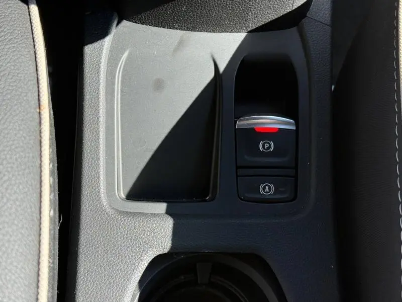 Gros plan sur la console centrale de la Renault Clio 2025, montrant les boutons du frein à main électrique et de l'arrêt automatique.