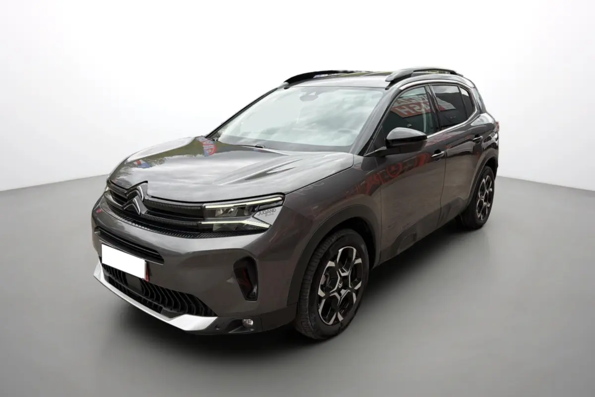 Citroën C5 Aircross gris platinium en 3/4 avant droit, avec jantes alu 18 pouces et barres de toit visibles.