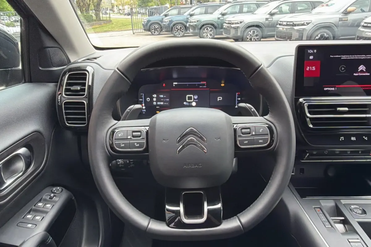 Vue intérieure centrée sur le volant cuir multifonctions d'un Citroën C5 Aircross 2025, avec tableau de bord digital.