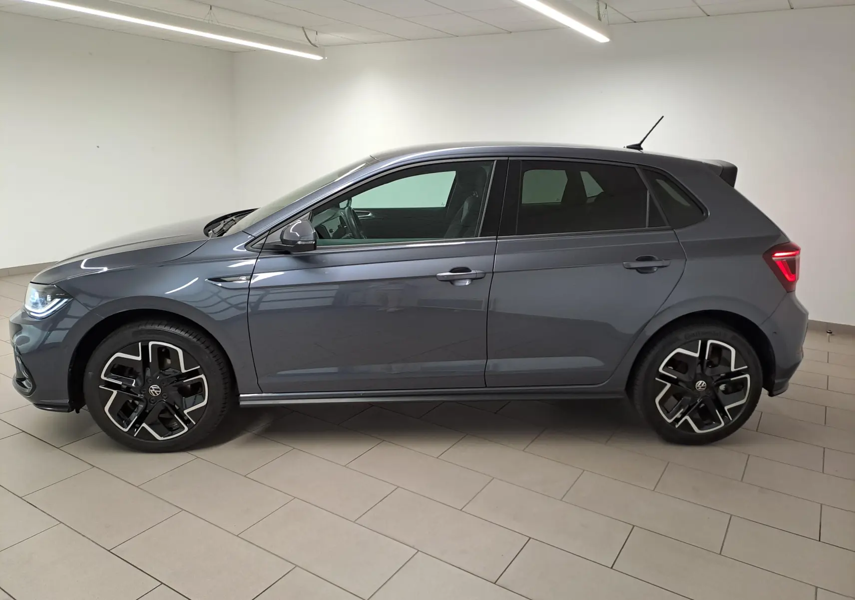 Profil droit d'une Volkswagen Polo 1.0 TSI 116 DSG7 R-Line Edition gris cendré métallisé avec jantes distinctives en intérieur neutre.