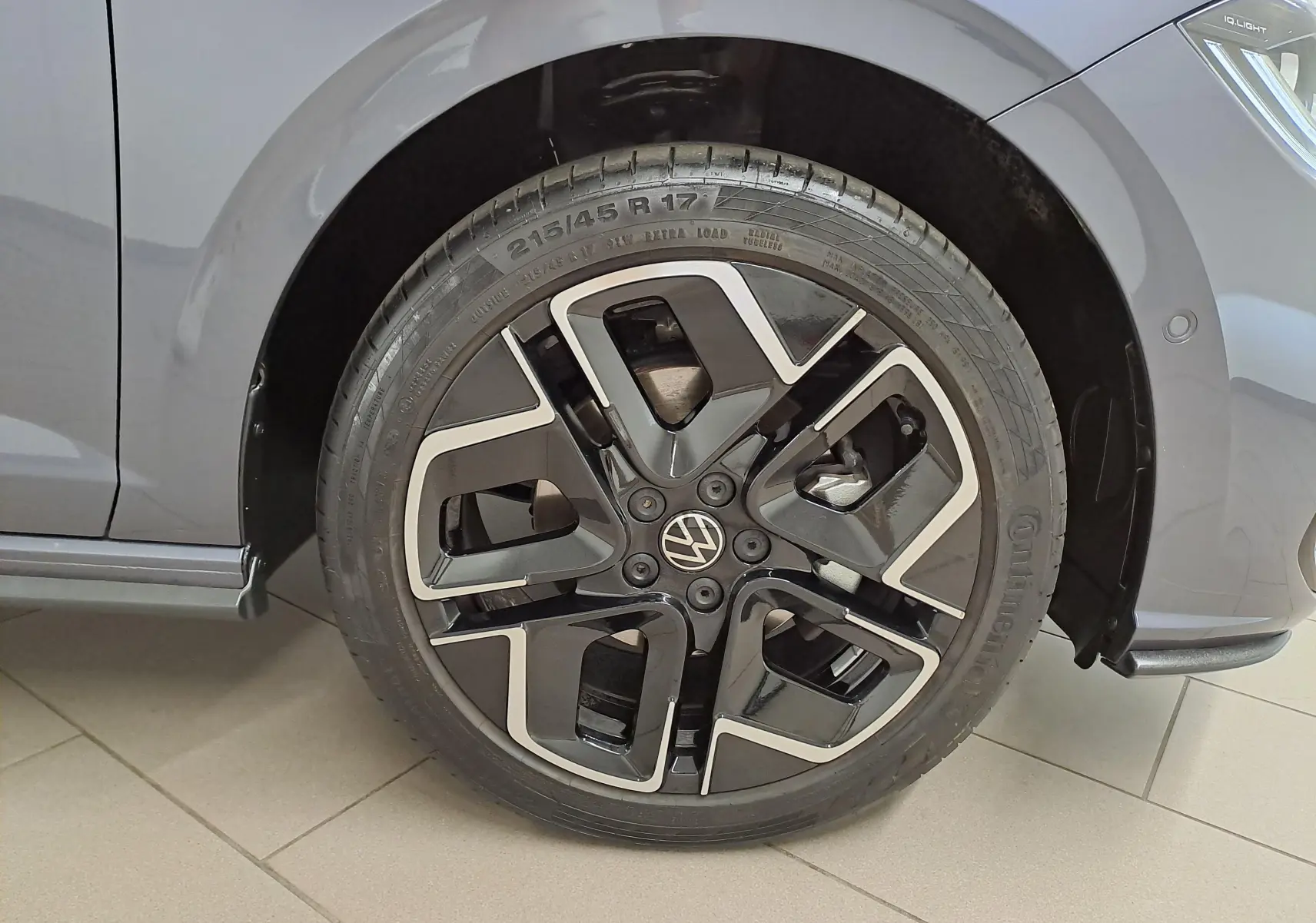 Gros plan sur la roue avant gauche d’une Volkswagen Polo gris cendré avec jante noire et argentée au design R-Line.