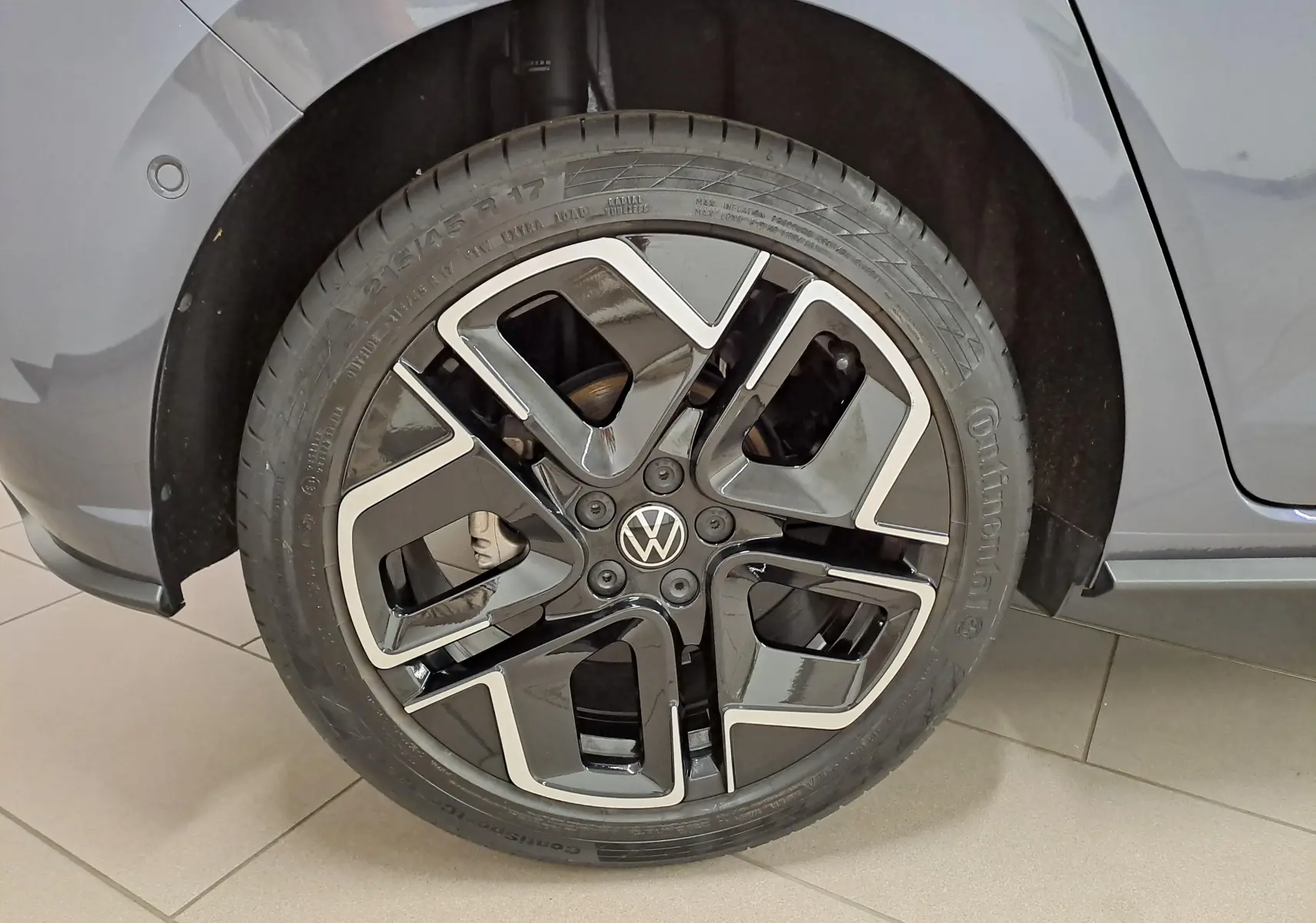 Gros plan sur la roue avant droite d’une Volkswagen Polo gris cendré avec jante alliage noire et argentée.