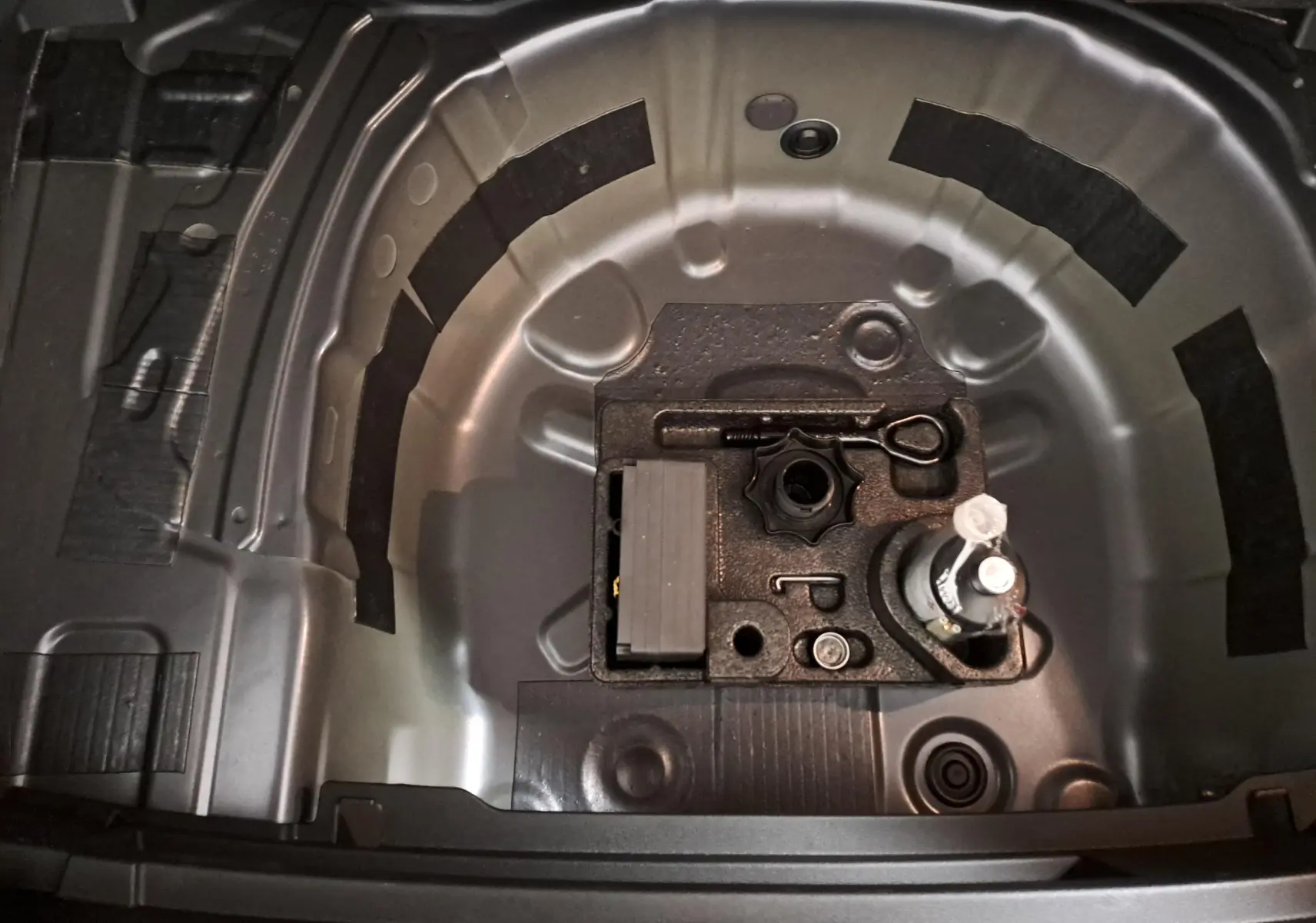 Vue plongeante sur le compartiment de roue de secours vide d'une Volkswagen Polo gris cendré, version R-Line Edition.