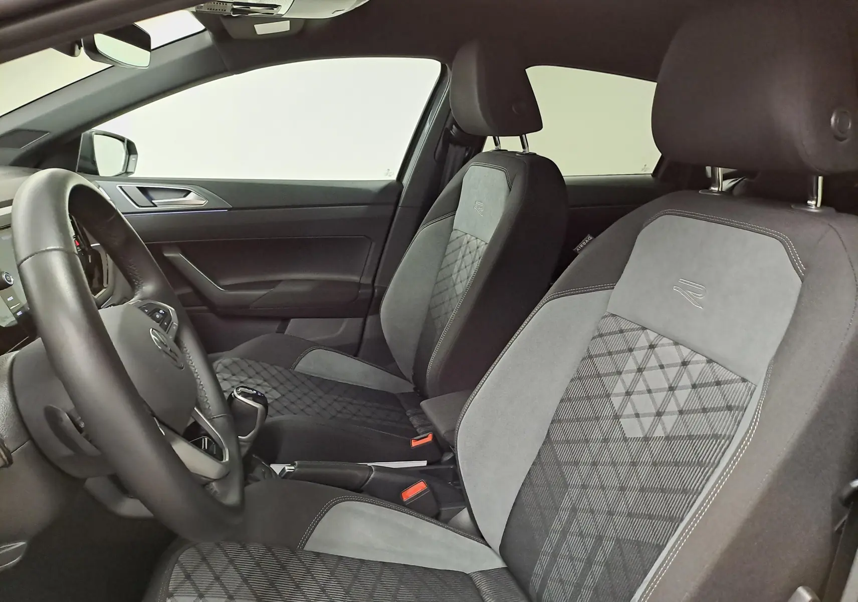 Vue intérieure côté gauche de la Volkswagen Polo 1.0 TSI R-Line 2025 avec sièges tissu et alcantara gris et volant cuir.