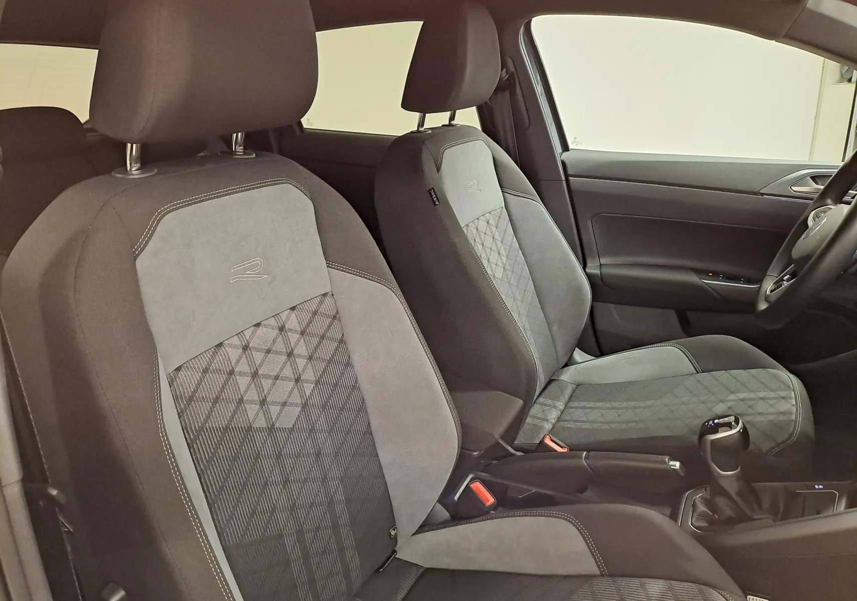 Vue intérieure côté droit des sièges avant gris avec surpiqûres et logo R de la Volkswagen Polo 2025 R-Line Edition.