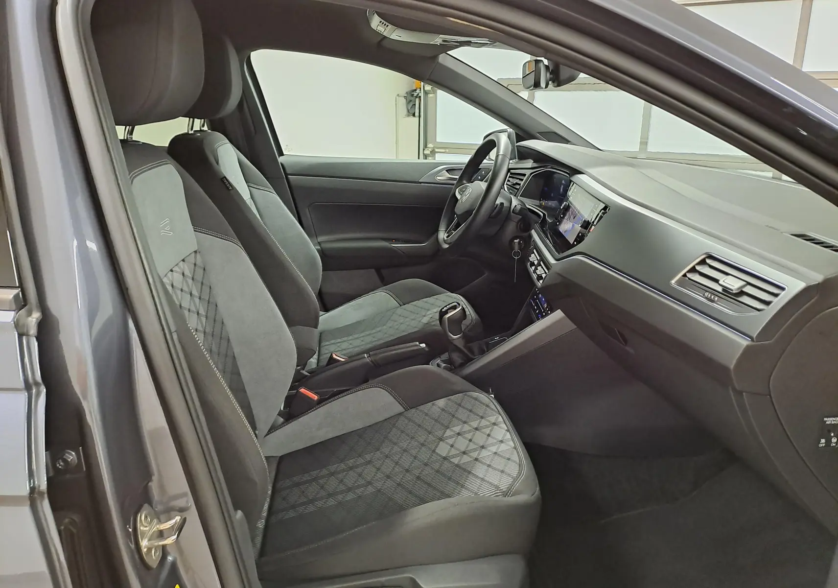 Vue intérieure côté conducteur de la Volkswagen Polo gris cendré, sièges R-Line avec surpiqûres et tableau de bord moderne.