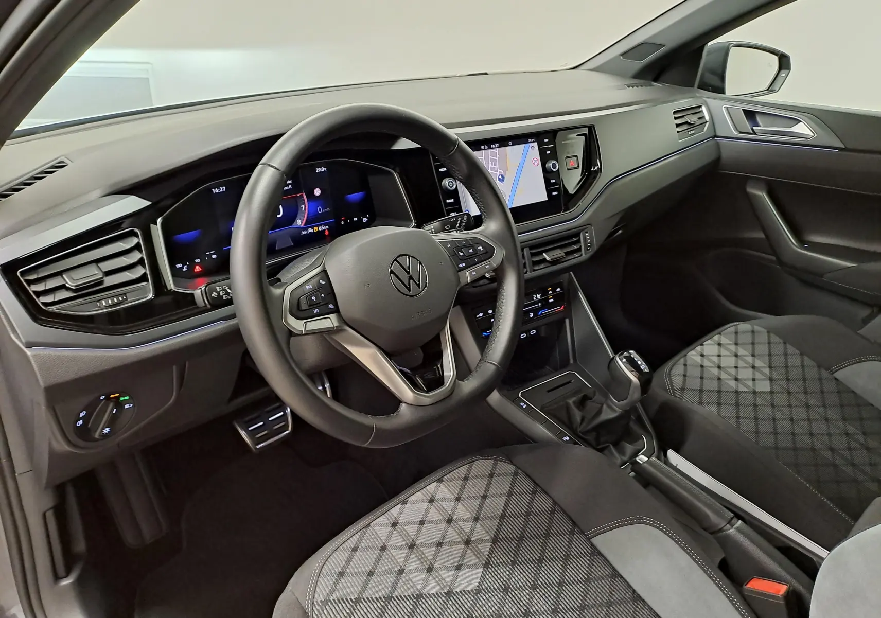 Intérieur de la Volkswagen Polo 2025 vu côté conducteur, tableau de bord numérique et sellerie tissu à motif gris.