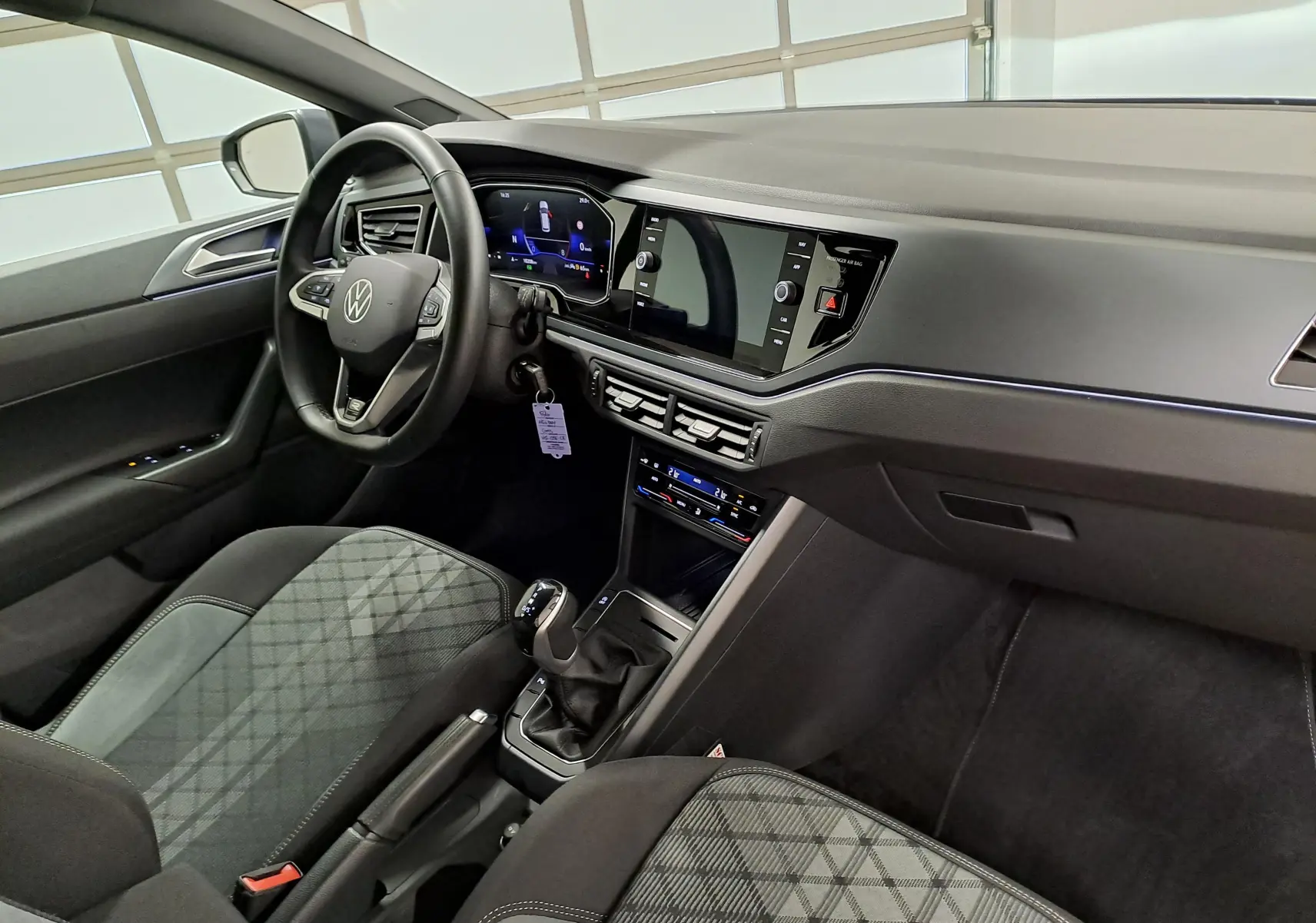 Vue intérieure côté conducteur de la Volkswagen Polo 1.0 TSI R-Line avec tableau de bord numérique et sellerie tissu à motifs.