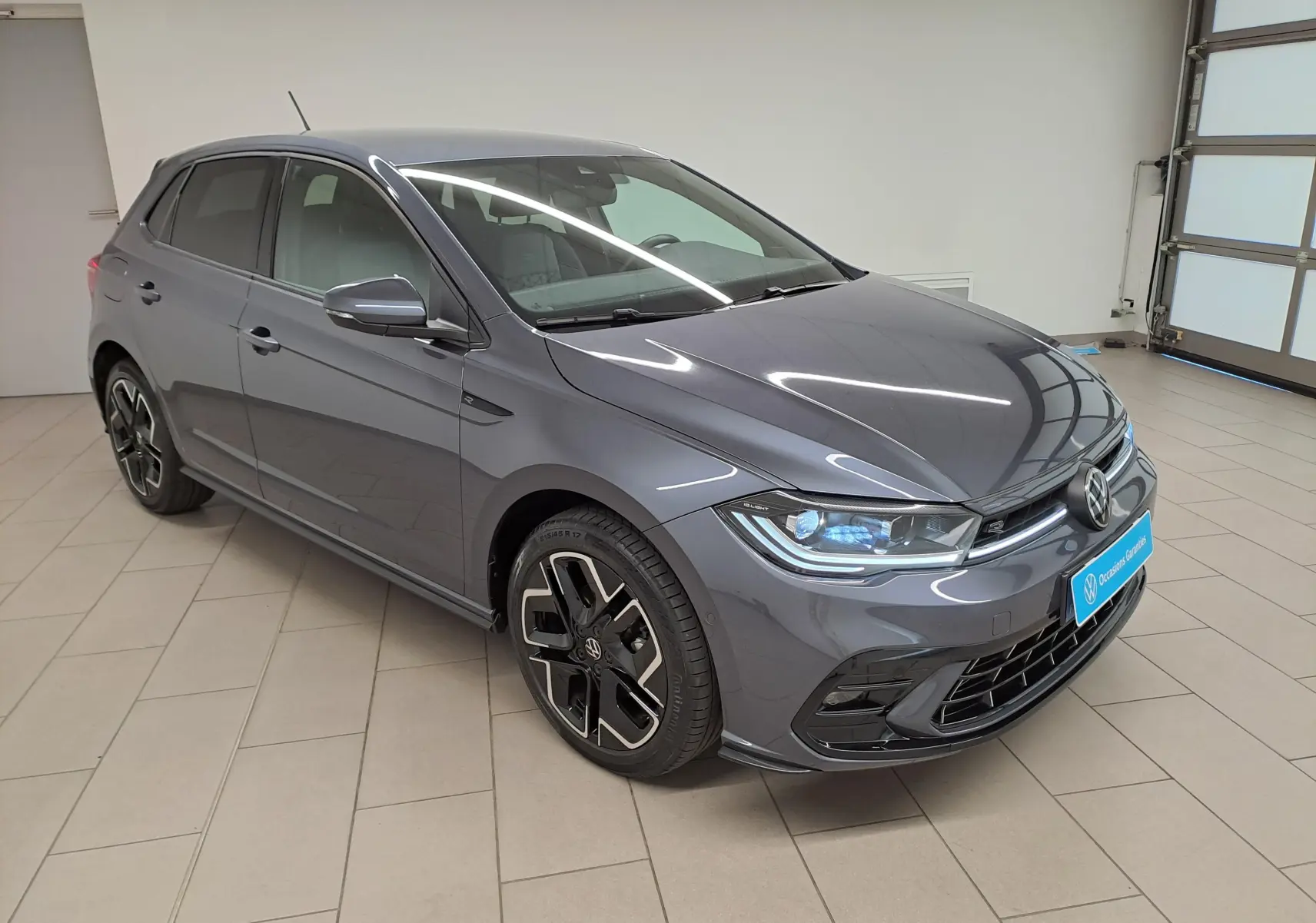 Volkswagen Polo 1.0 TSI R-Line gris cendré vue 3/4 avant droit en intérieur avec jantes distinctives.