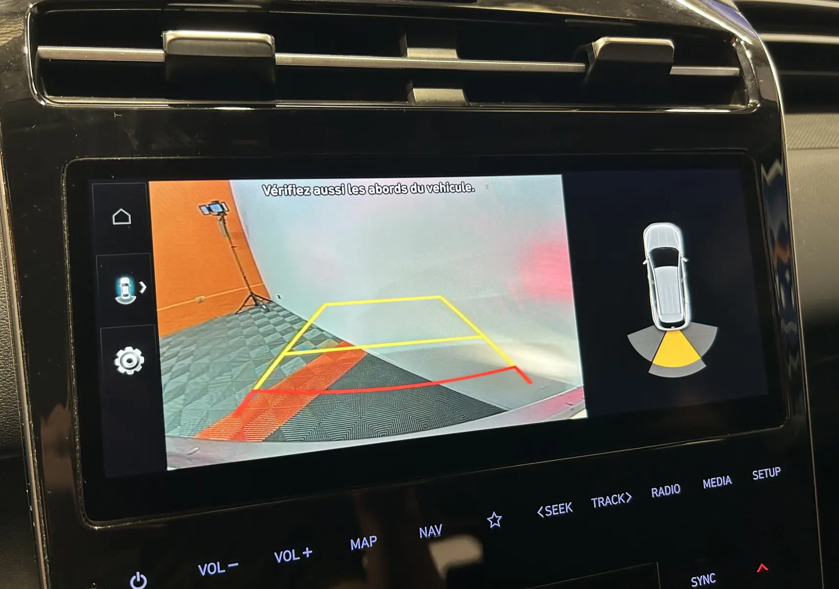 Écran de caméra de recul du Hyundai Tucson Hybrid 2022 affichant les lignes de guidage et l'alerte de proximité arrière.