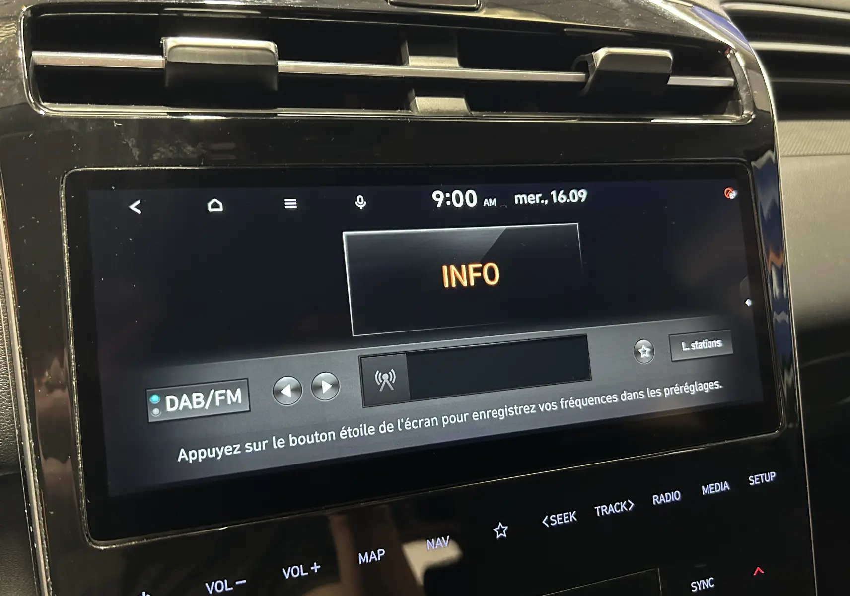 Écran tactile central du Hyundai Tucson Hybrid 2022 en gros plan, affichant le menu radio DAB/FM sur fond noir brillant.