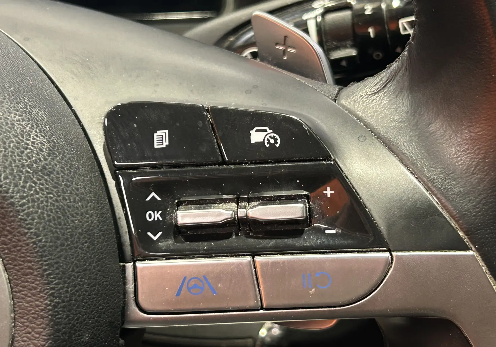 Gros plan sur les commandes de régulateur de vitesse au volant noir du Hyundai Tucson Hybrid 2022.