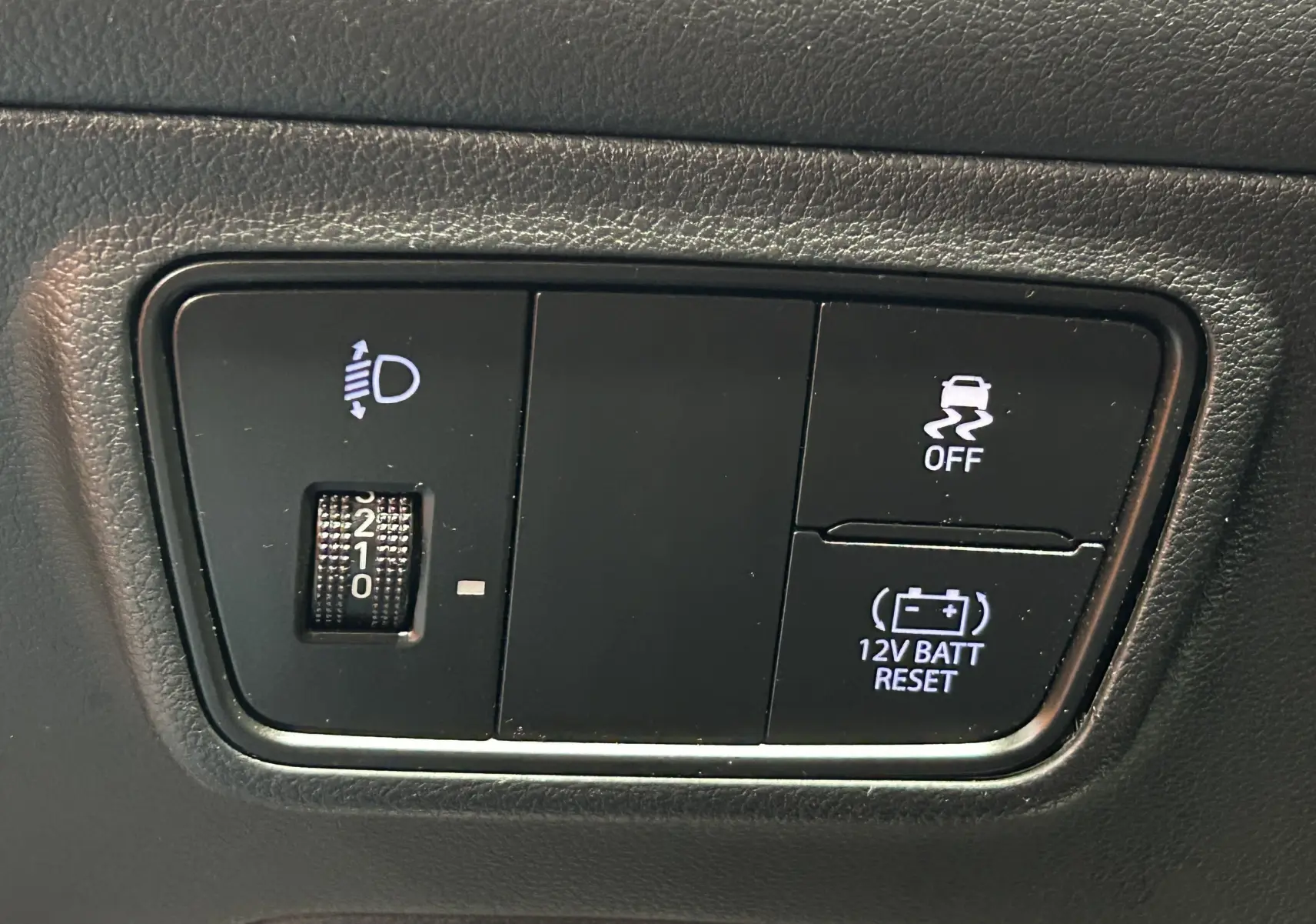 Gros plan sur les commandes intérieures du Hyundai Tucson Hybrid 2022, avec réglage des phares et bouton de désactivation de l'ESP.