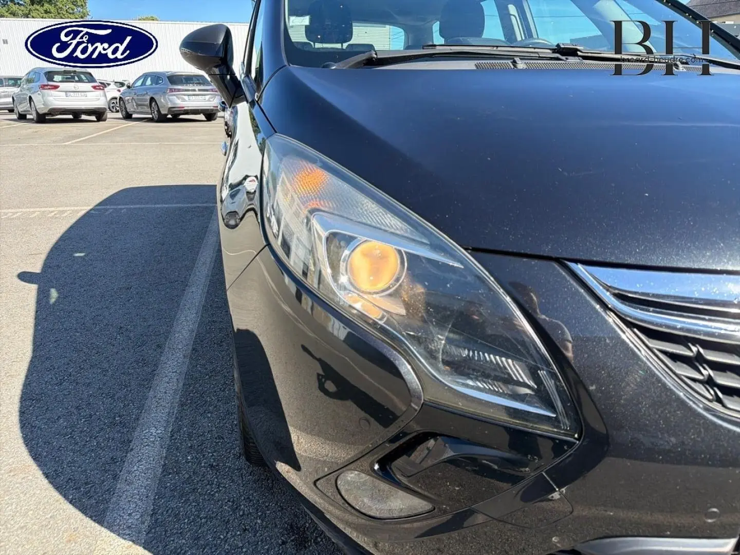 Gros plan sur l'avant gauche gris métal de l'Opel Zafira Tourer avec phare allumé et calandre chromée visible.