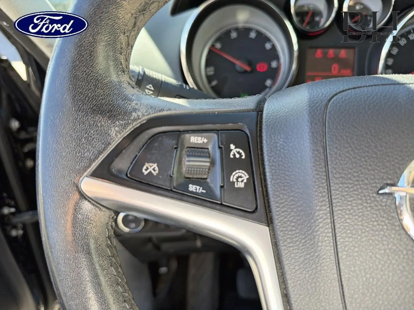 Gros plan sur le volant cuir gris de l'Opel Zafira Tourer 2013 avec commandes de régulateur de vitesse visibles.