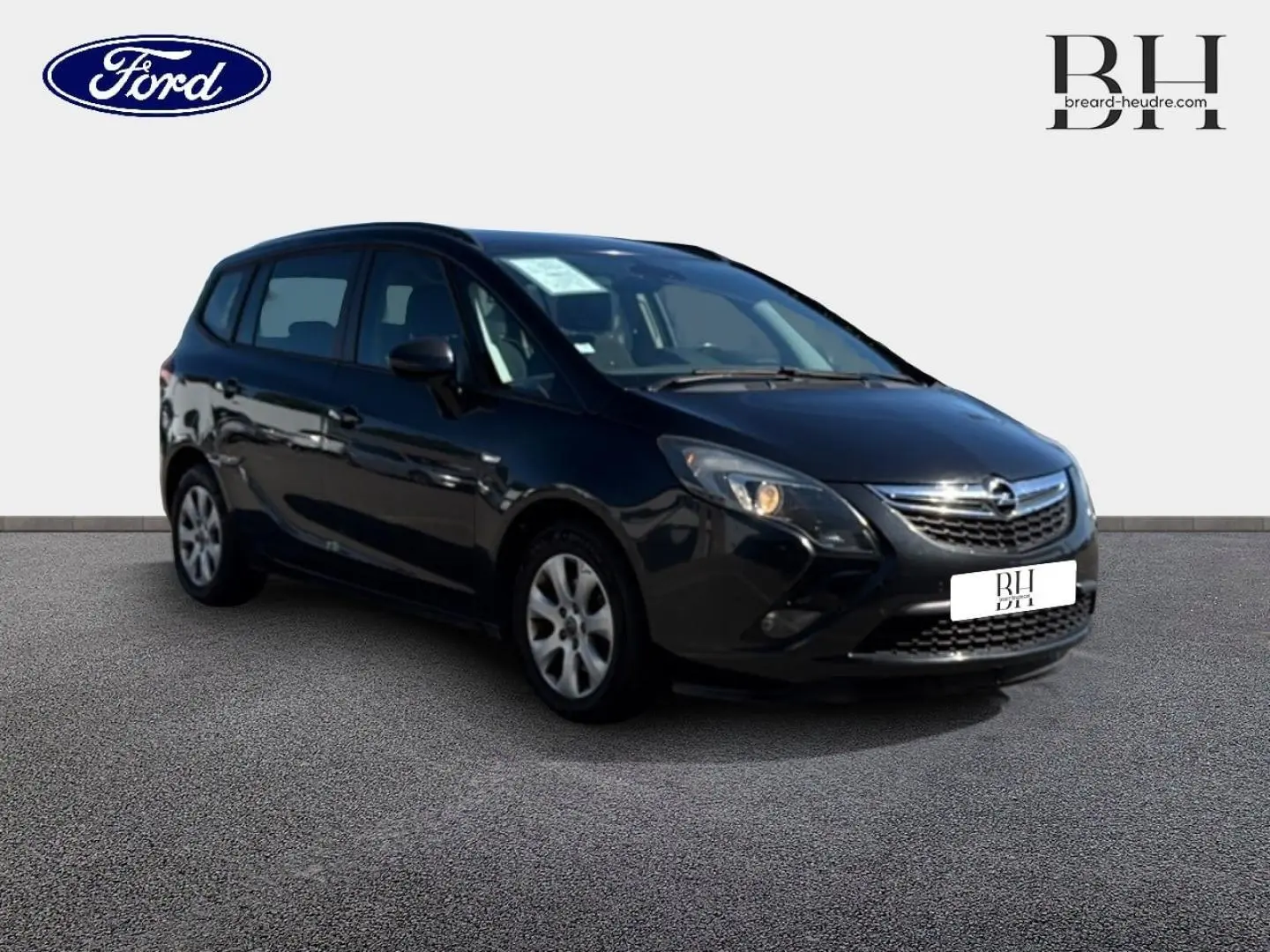 Opel Zafira Tourer gris métal vue 3/4 avant droit, avec calandre chromée et phares allumés.