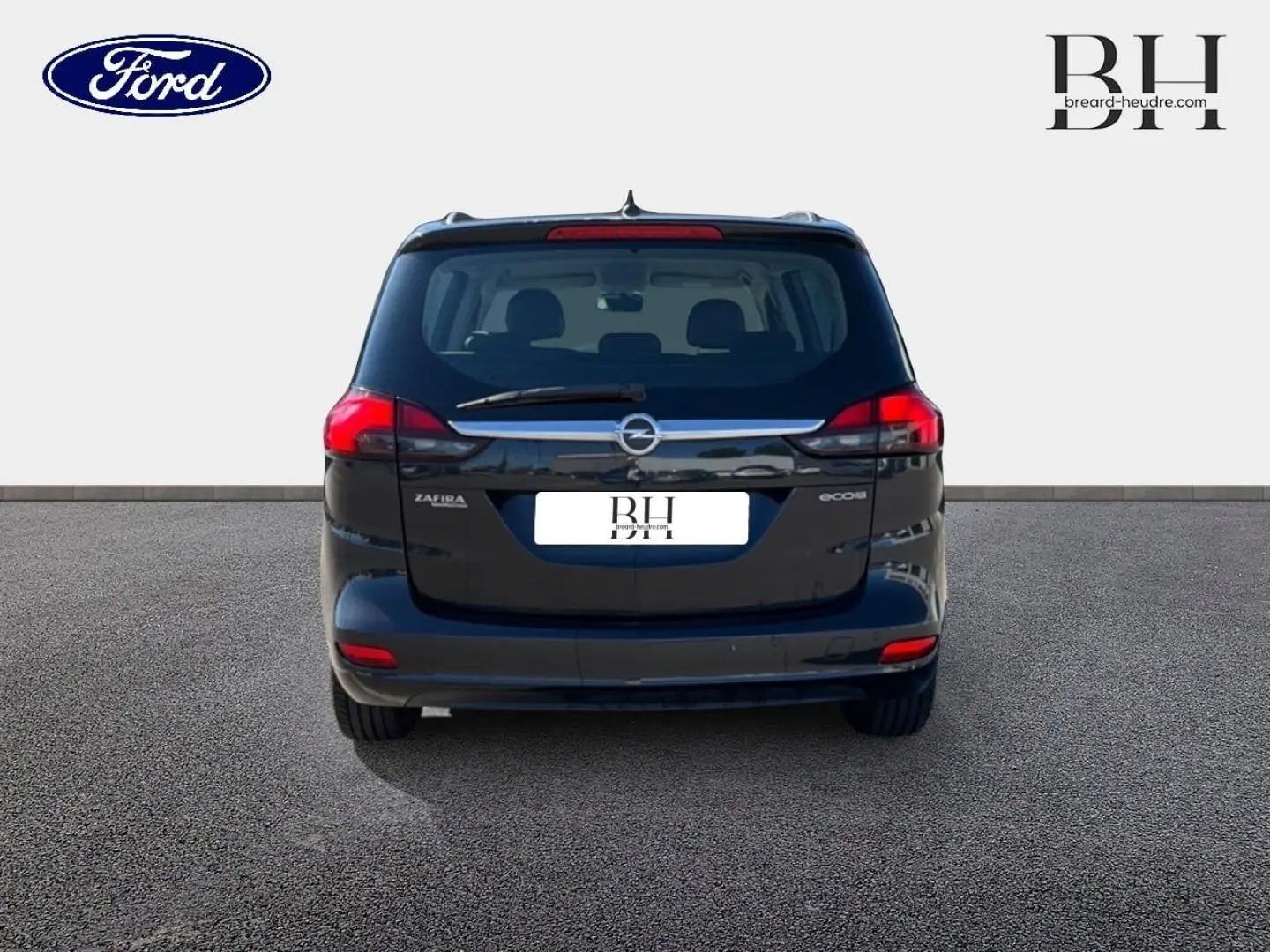 Vue arrière d'un Opel Zafira Tourer gris métal, montrant ses feux rouges et la lunette arrière avec essuie-glace.