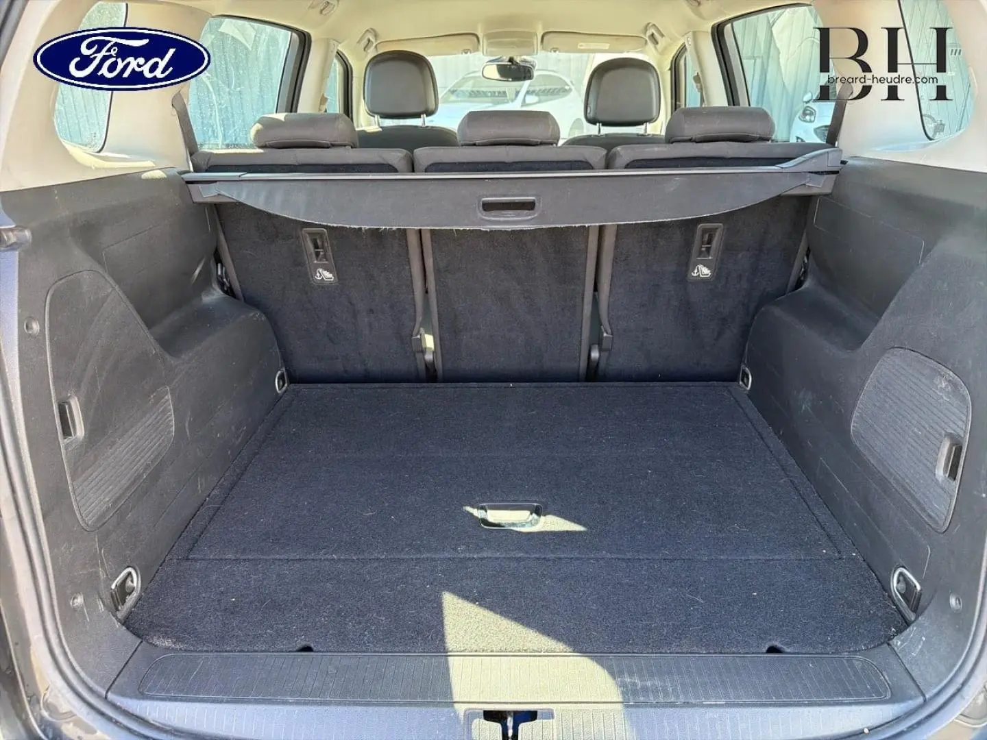 Coffre spacieux vu de l'arrière avec banquette arrière noire et cache-bagages dans un Opel Zafira Tourer gris métal.