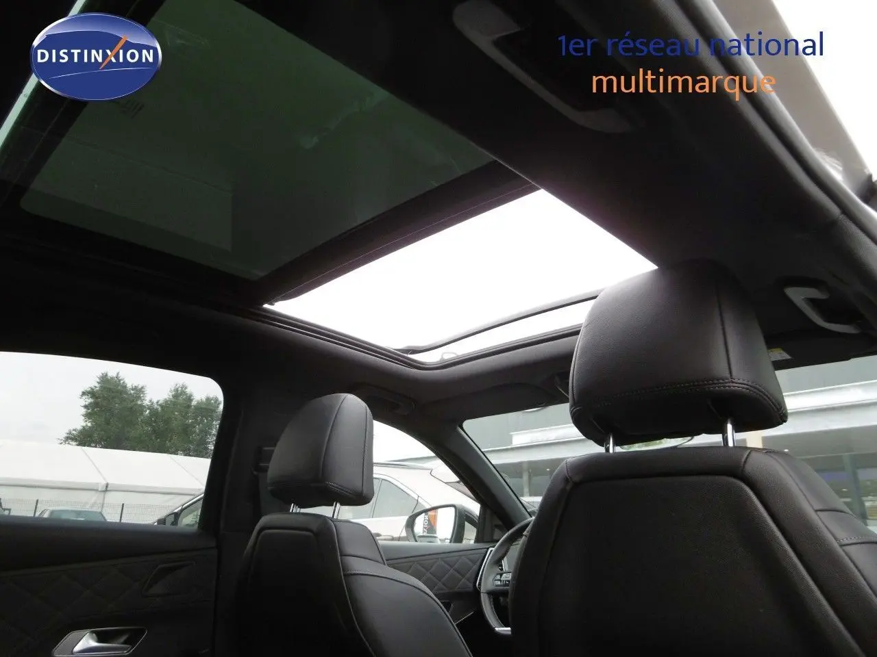 Vue intérieure du DS7 Crossback 2021 montrant les sièges avant en cuir noir et le toit panoramique ouvert.