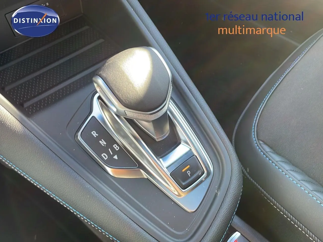Le levier de vitesse automatique du Renault Captur E-Tech hybride 2025, avec surpiqûres bleues sur la console noire.