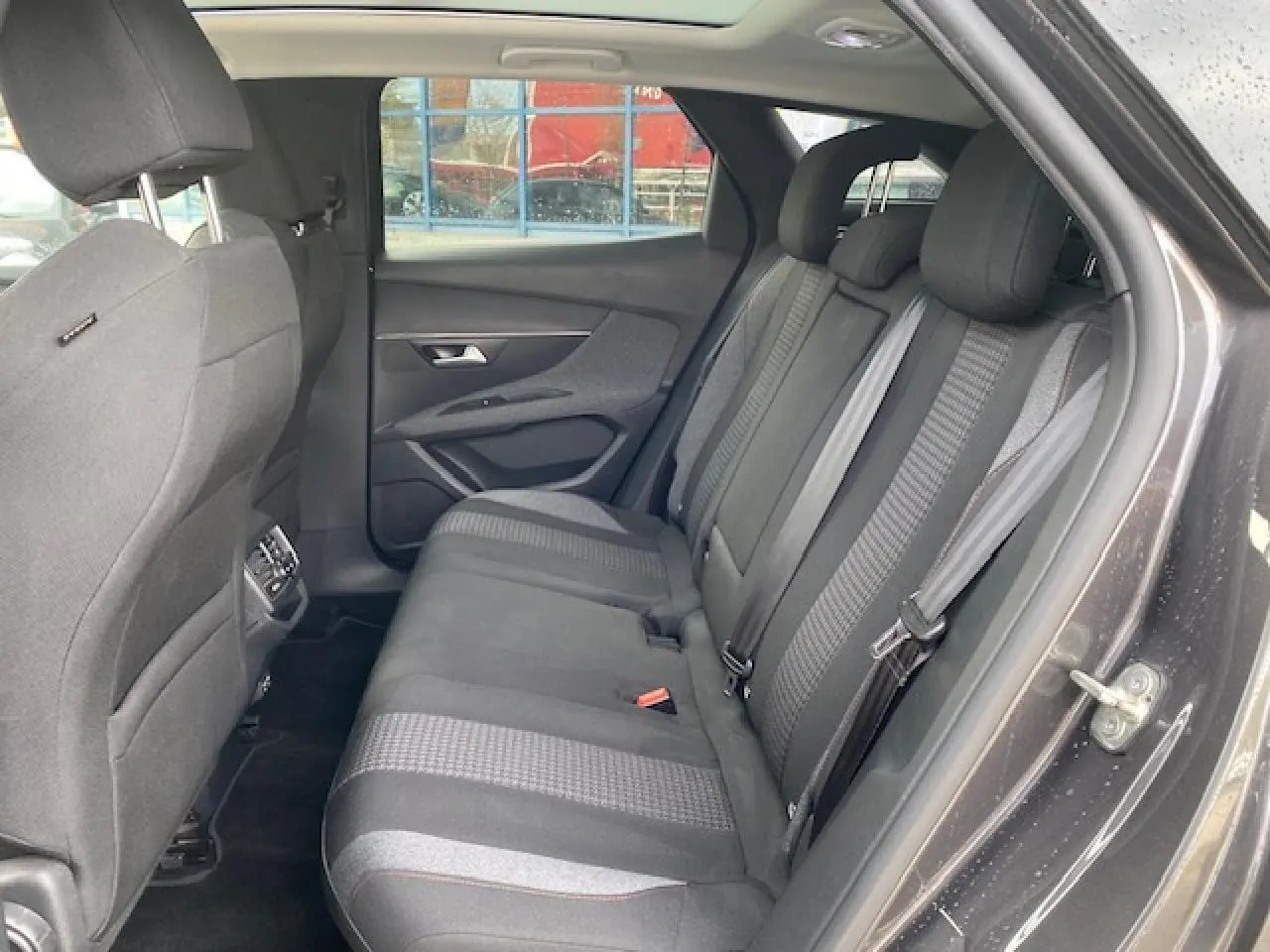 Vue intérieure côté droit sur la banquette arrière grise du Peugeot 3008 2021 avec toit ouvrant panoramique visible.