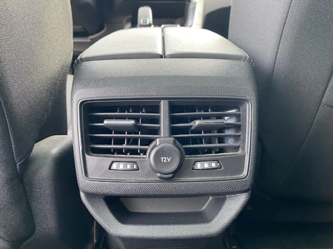 Vue rapprochée des aérateurs arrière et prise 12V entre les sièges avant d'un Peugeot 3008 gris platinium.