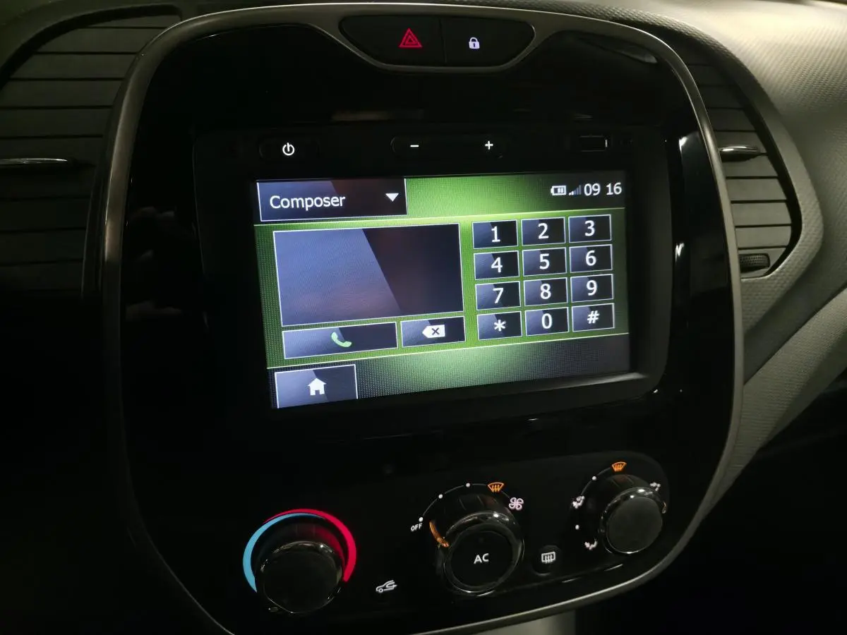 Vue rapprochée de l'écran tactile du système MédiaNav et des commandes de climatisation du Renault Captur noir 2014.